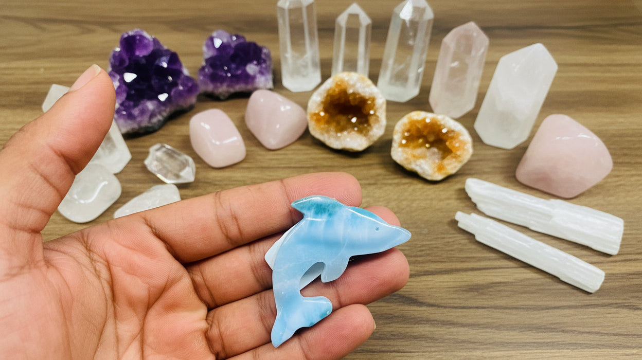 Hand holding a small blue dolphin figurine with a blurred background