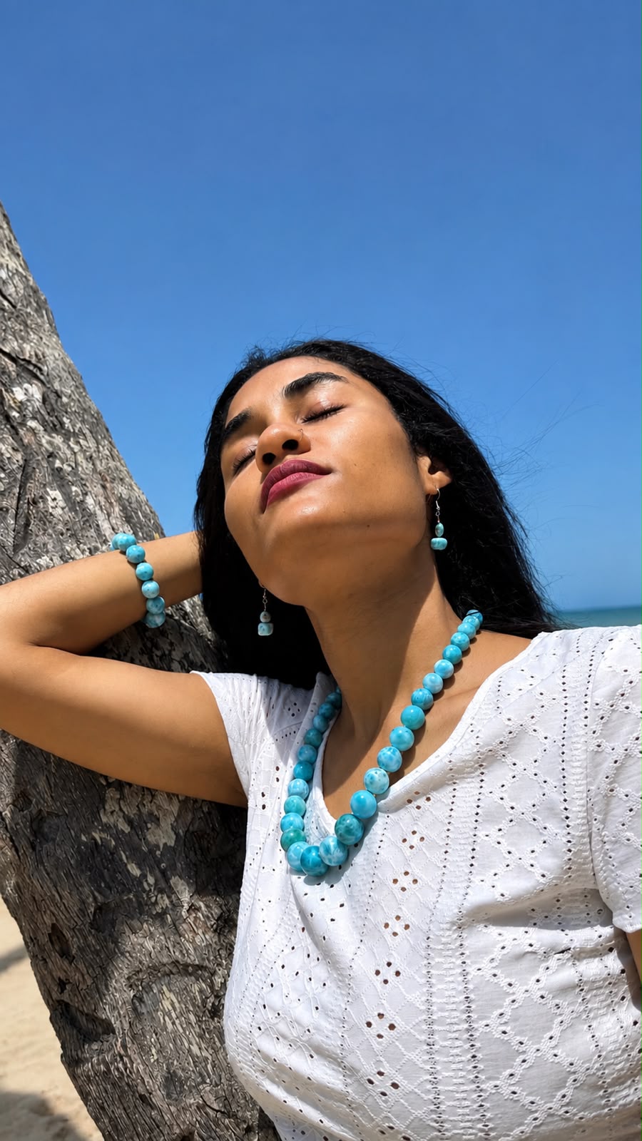 Woman wearing  Larimar Necklace jewelry against a clear blue sky