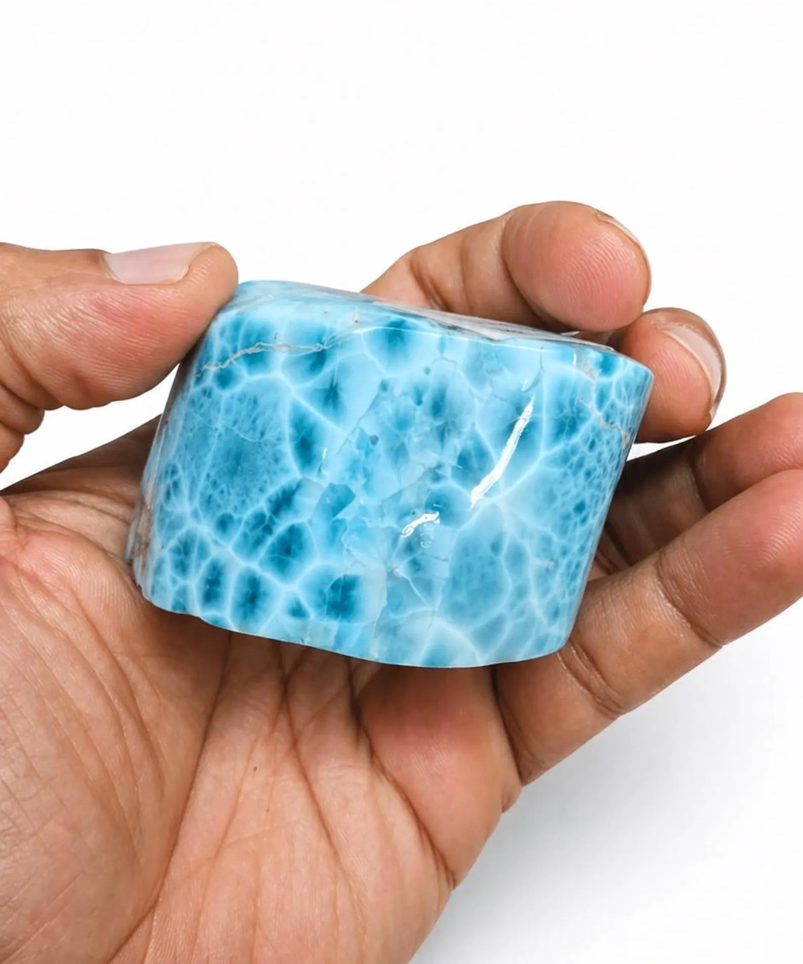A hand holding a Larimar Stone Freeform, set against a plain white background.