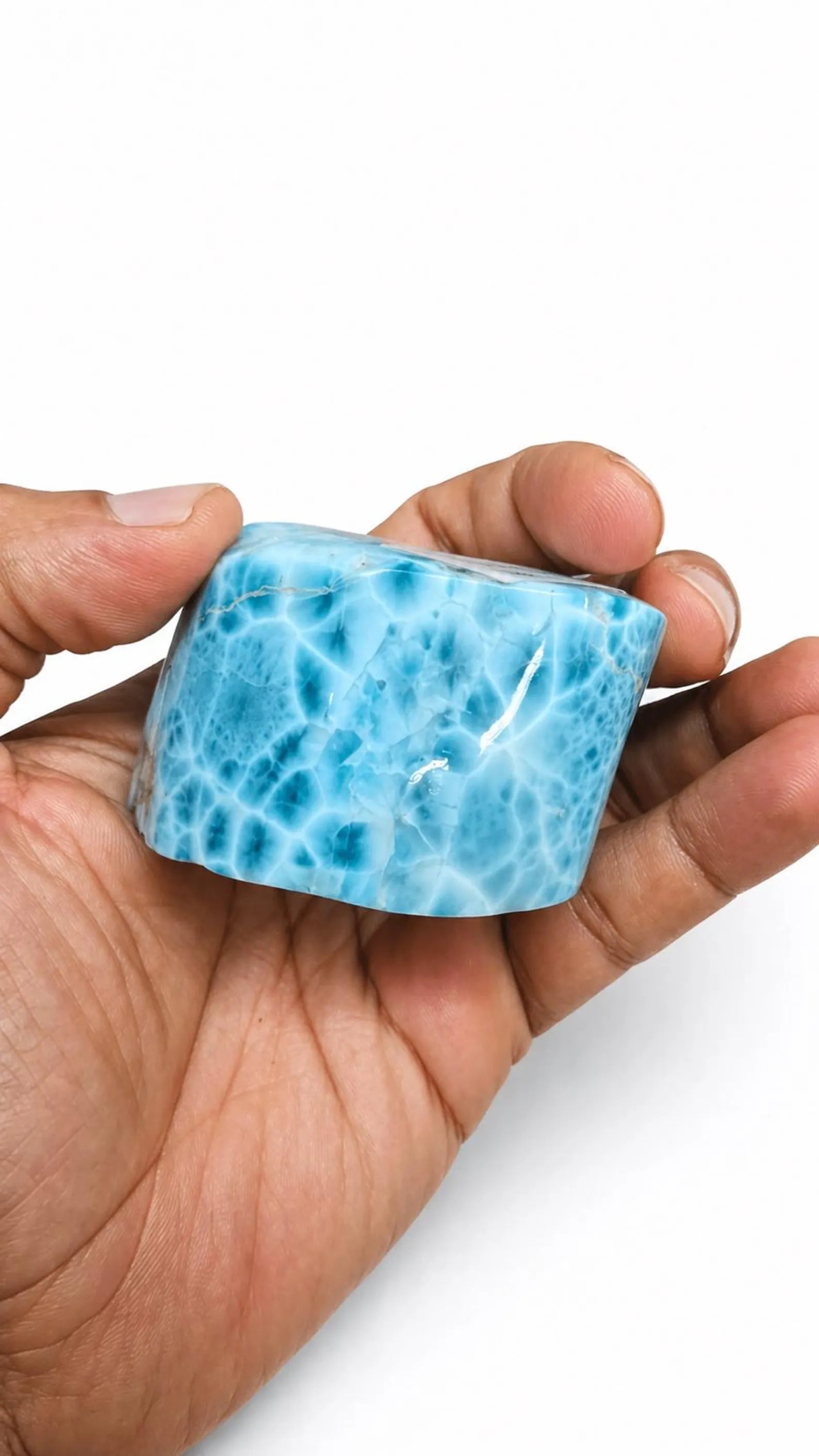 A hand holding a Larimar Stone Freeform, set against a plain white background.