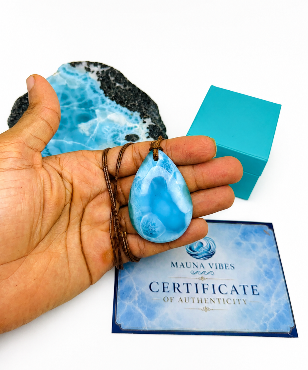 A hand holding a larimar necklace