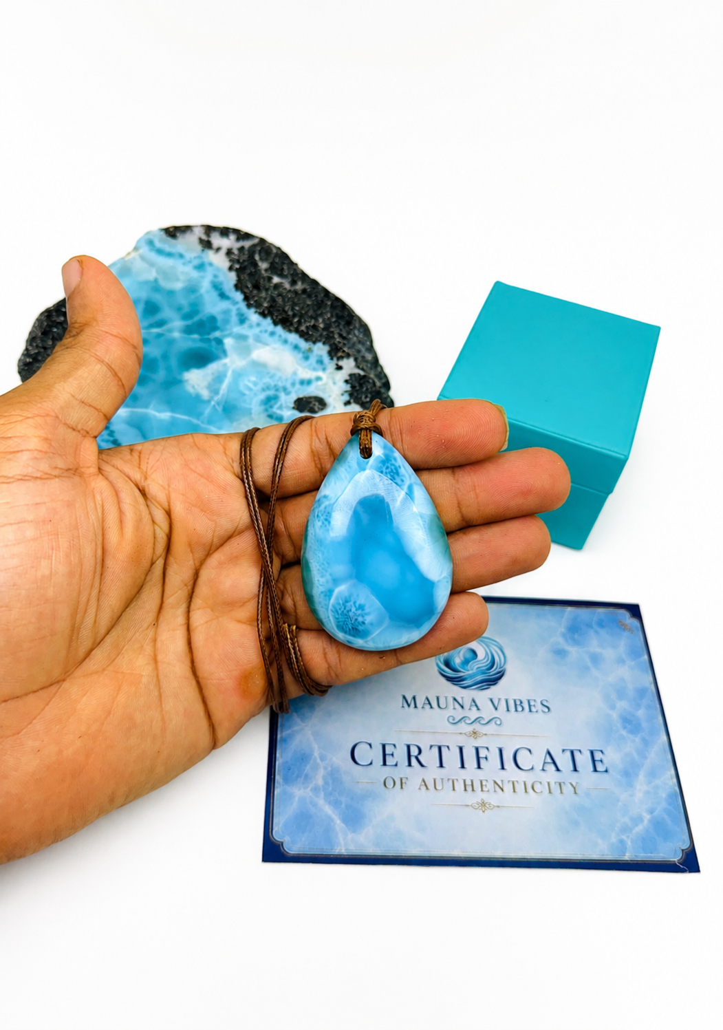 A hand holding a larimar necklace