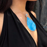 A woman wearing a high grade larimar necklace pendant 