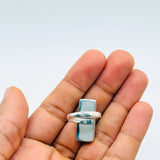 A silver ring with a rectangular light blue stone, held on the fingers of a hand against a plain light gray background.