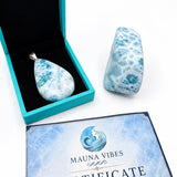 A teardrop-shaped marbled pendant in a turquoise box next to a matching polished stone, with a Certificate of Authenticity from Mauna Vibes on a white background.