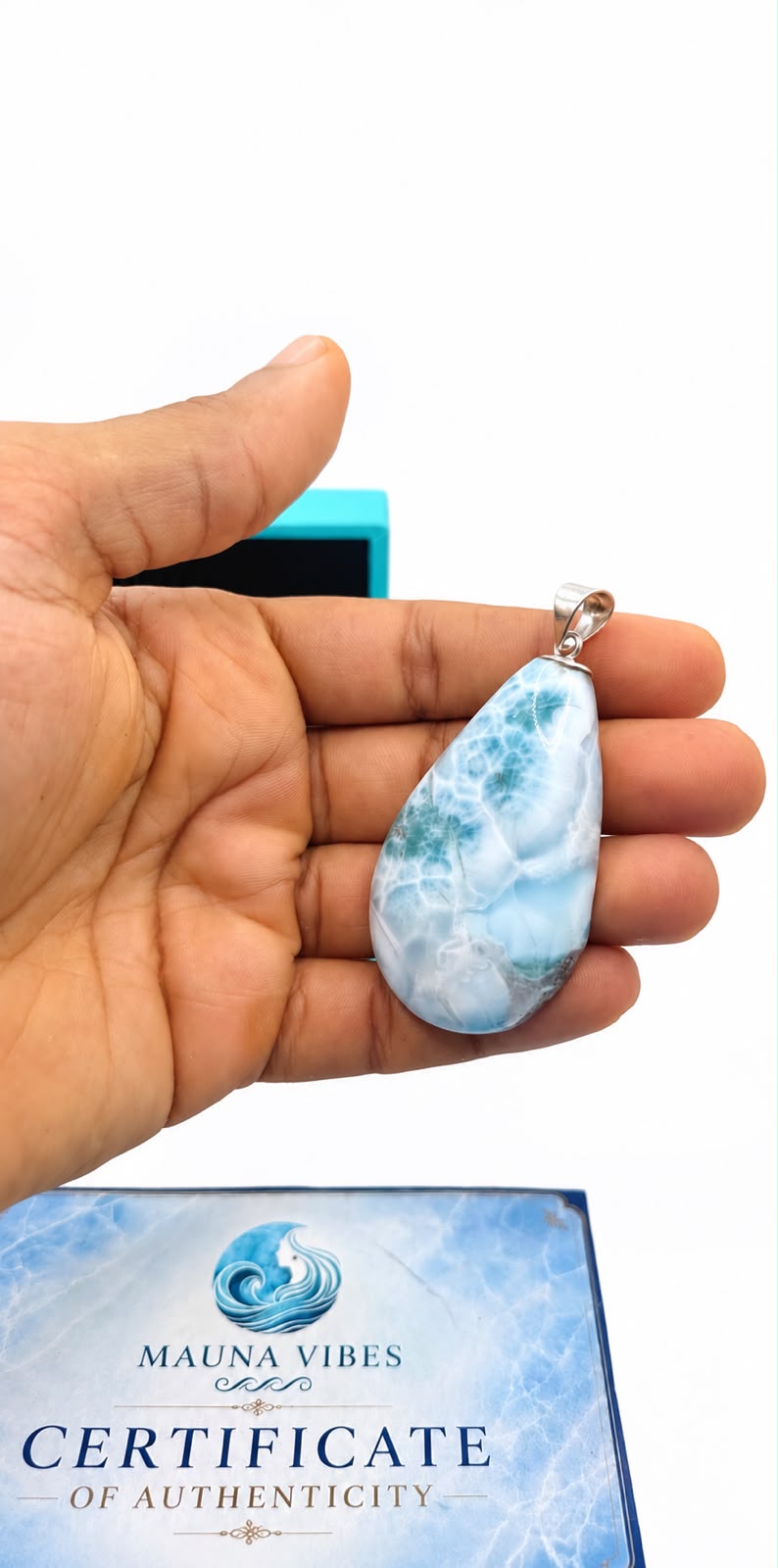 A hand holds a larimar stone teardrop-shaped pendant 