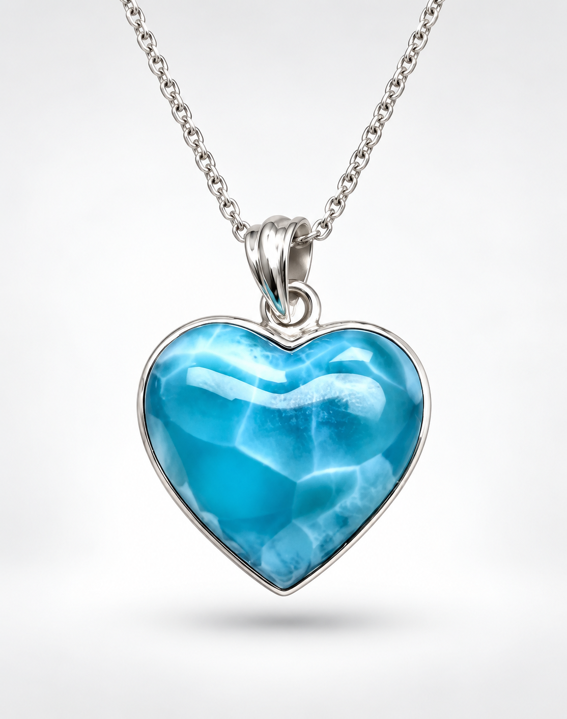 A Larimar Stone heart-shaped pendant necklace featuring a vibrant blue marbled gemstone in a polished silver bezel, suspended from a matching silver chain against a light gray background.