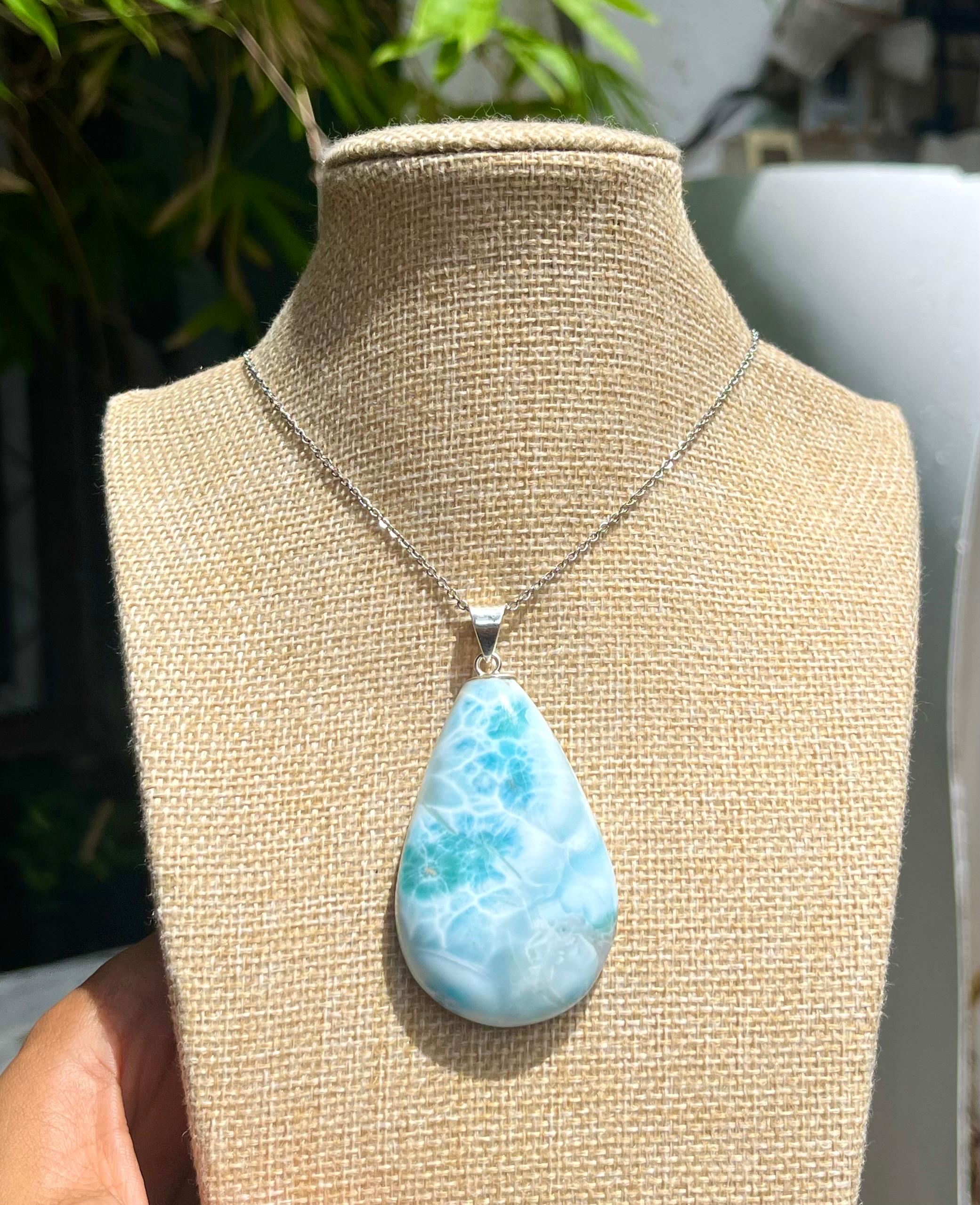 A teardrop-shaped Larimar pendant necklace with a light blue and white.