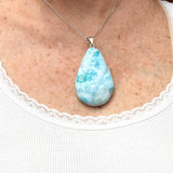A teardrop-shaped Larimar pendant worn by a woman