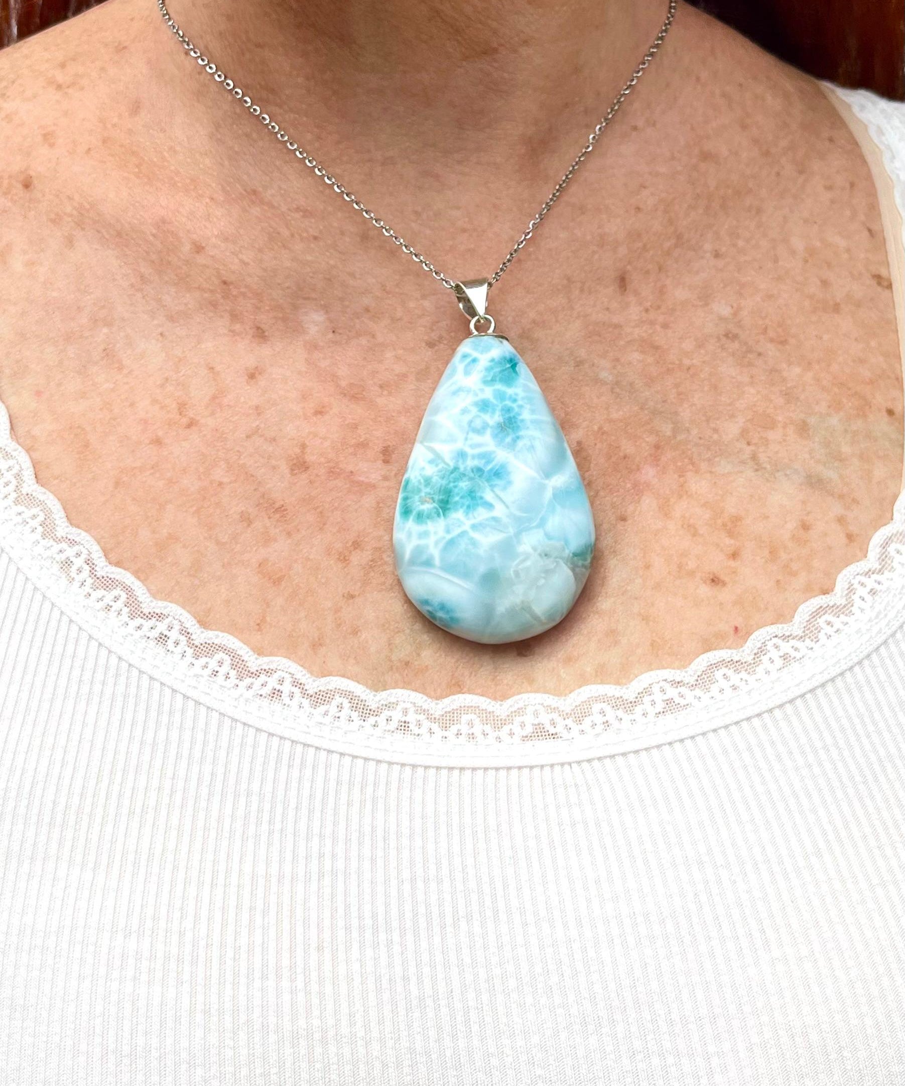 A teardrop-shaped Larimar pendant worn by a woman