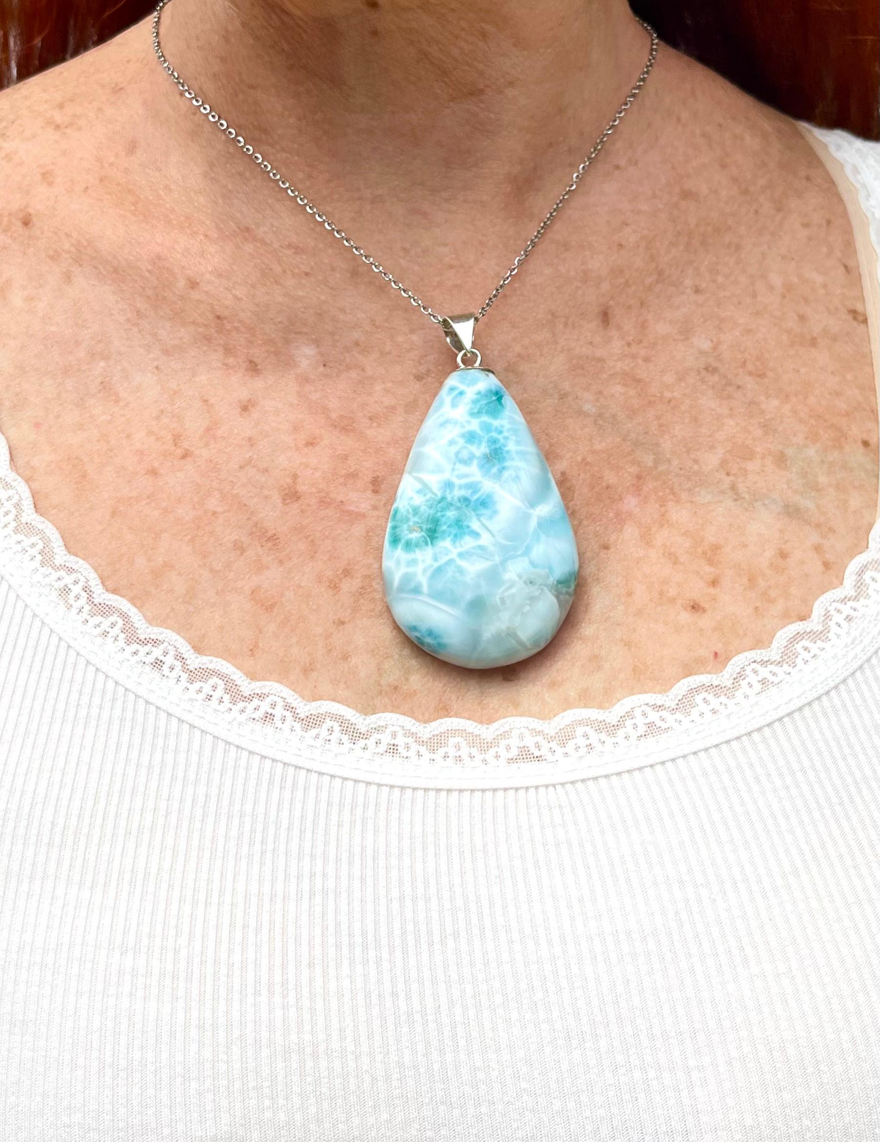 A teardrop-shaped Larimar pendant worn by a woman