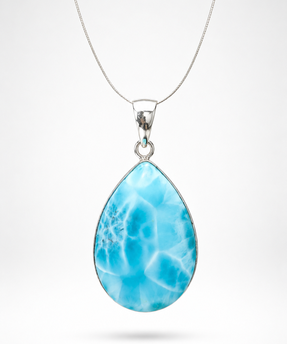 A Larimar teardrop-shaped pendant necklace featuring a vibrant blue marbled stone with white veining, suspended from a delicate silver chain against a light gray background.