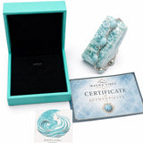 A Mauna Vibes authenticated jewelry box set featuring a turquoise and white baroque stone clutch purse with a silver chain, an open turquoise presentation box with a black velvet interior, a Certificate of Authenticity, and an authenticity card on a white background.