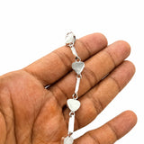 A silver-toned chain bracelet with small heart-shaped links, held in a person's hand against a plain white background.