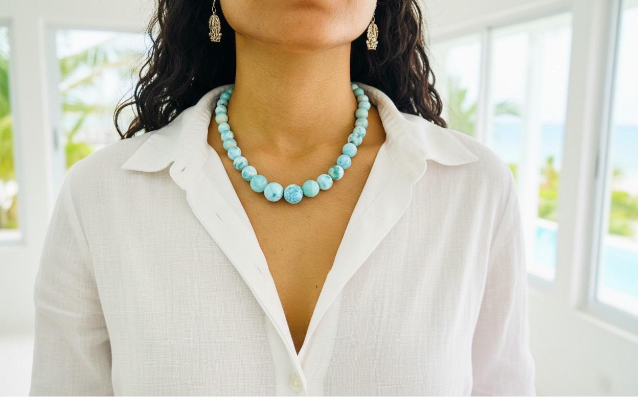 Person wearing a larimar beaded necklace with a blurred outdoor background