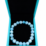 A Larimar
 beaded bracelet displayed inside an open turquoise jewelry box with a black interior, set against a plain white background.