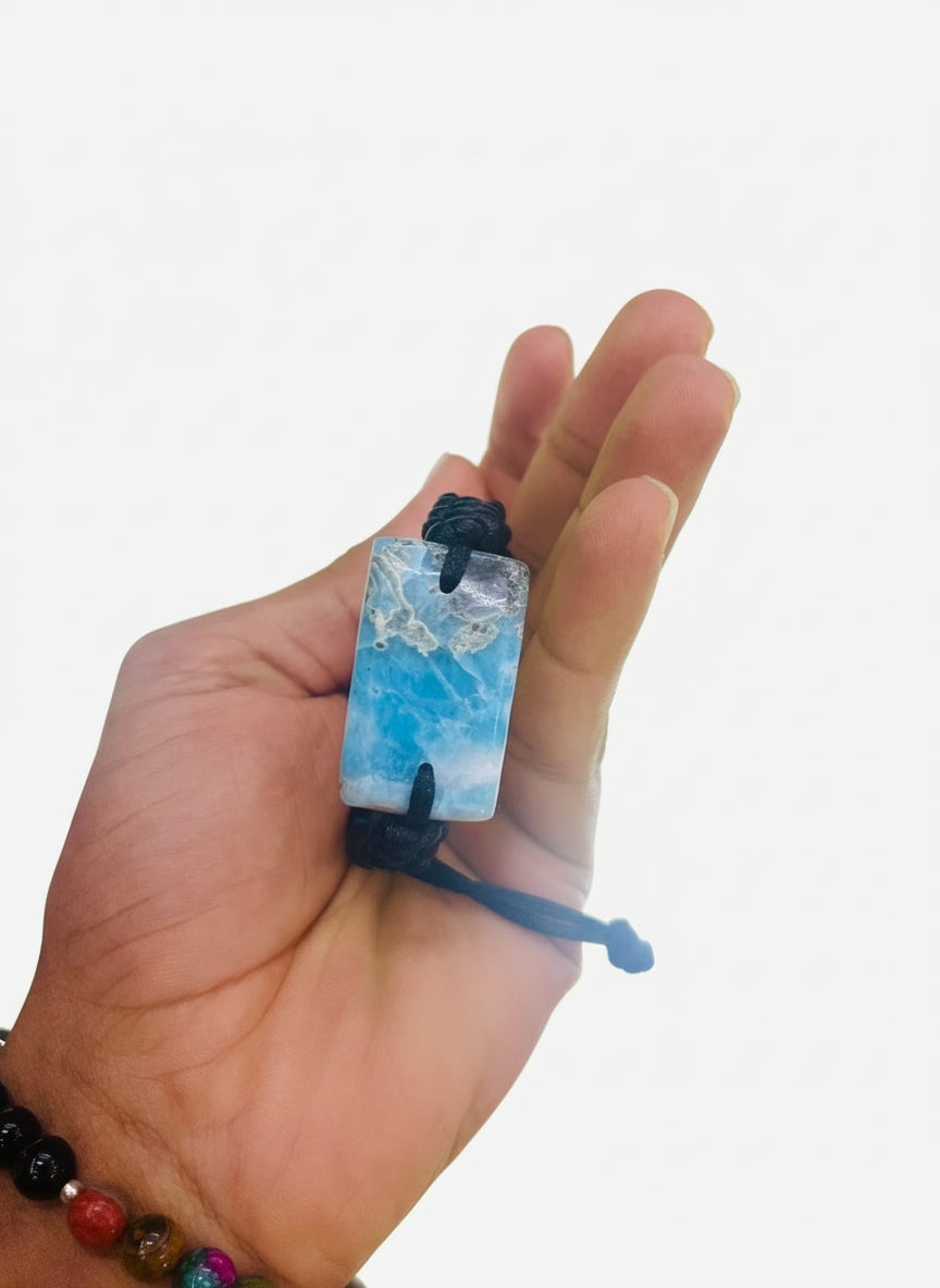 Hand holding a blue and white  larimar  baracelet with a blurred background