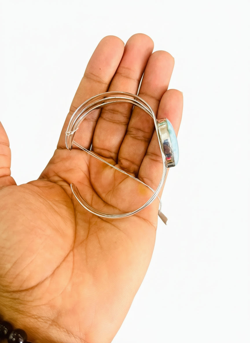 Hand holding a silver hoop earring with a blurred background