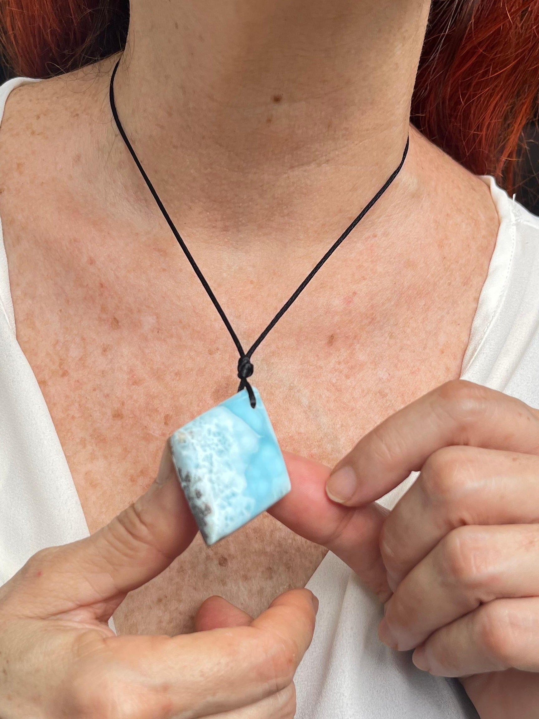 Person holding a blue Larimar
 pendant with a blurred background