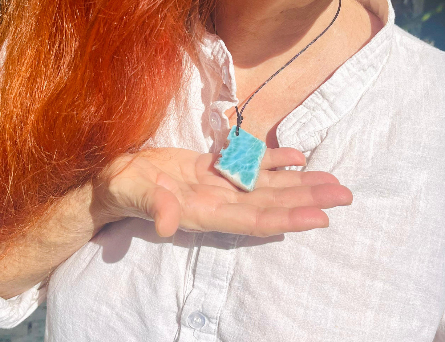 Person holding a blue pendant with a blurred background