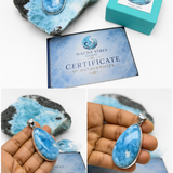 A collage showing a blue stone pendant with a silver bezel, displayed on a blue-and-black mineral specimen, next to a turquoise branded box and a certificate card. Two inset photos show a hand holding the pendant for scale and detail.