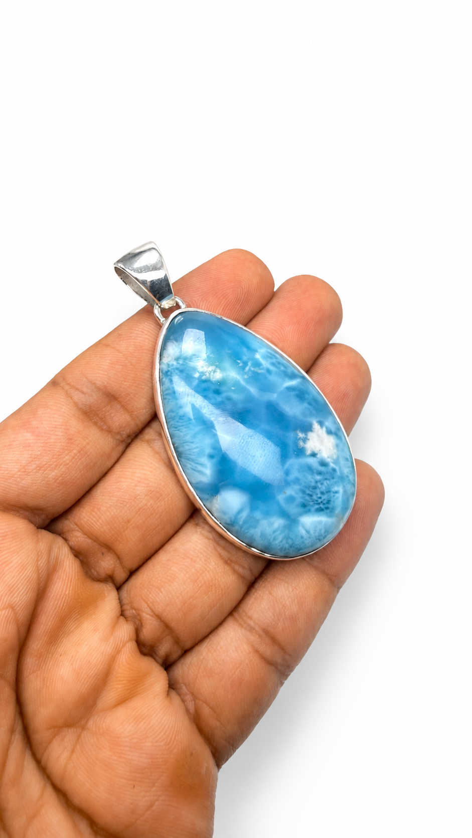 A silver oval pendant with a marbled blue and white stone, held in a person's hand against a plain white background.