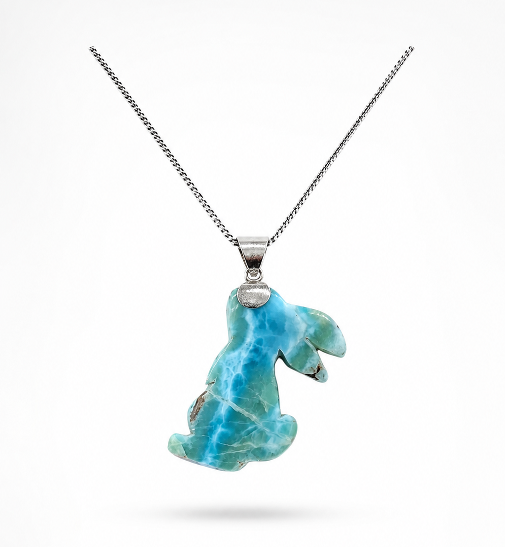 A silver chain necklace featuring a Larimar pendant with a Rabbit carved from  shown against a plain white background.