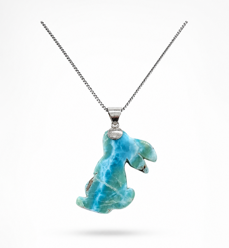 A silver chain necklace featuring a Larimar pendant with a Rabbit carved from  shown against a plain white background.