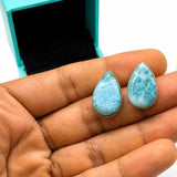 Hand holding Natural Larimar teardrop stud earrings handcrafted in solid 925 sterling silver with genuine Dominican Larimar gemstones displayed in a luxury jewelry gift box.