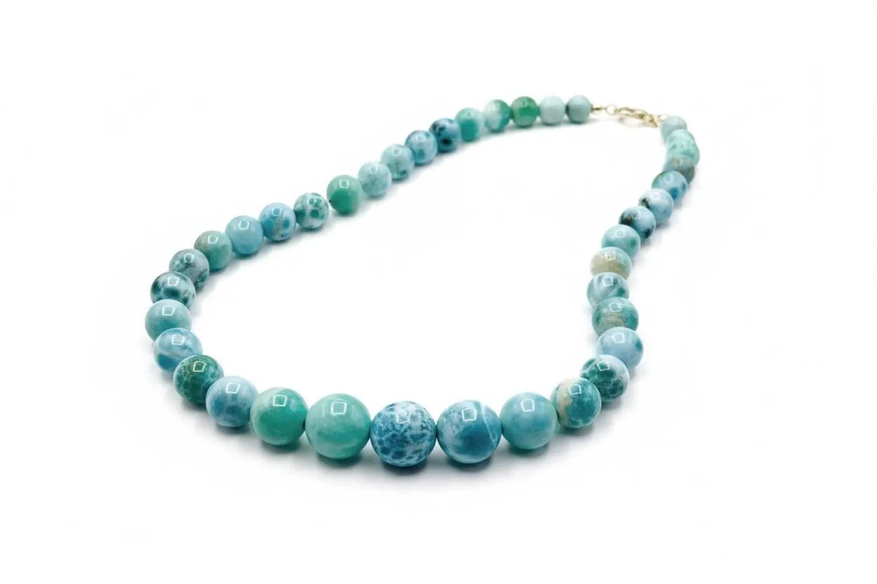 A beaded larimar necklace made of round turquoise-blue and green marbled beads with a small gold clasp, displayed on a clean white background.