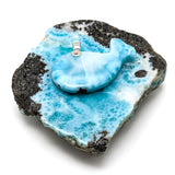 A whale-shaped pendant in light blue and white marbled resin, displayed on a decorative black and white marbled stone base against a white background.