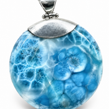 A round pendant featuring a blue and white coral-like marbled pattern, suspended from a textured silver bail, shown against a plain white background.