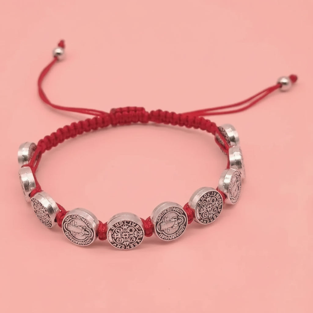 Bracelet with silver beads and red cord on a white background