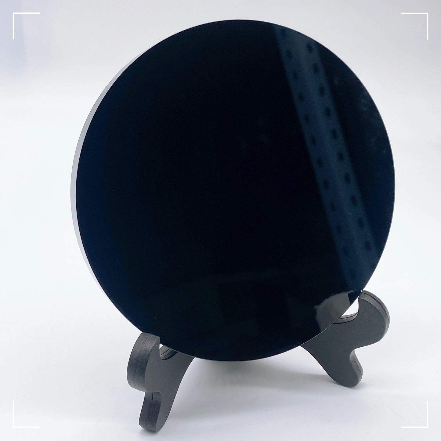 Black circular object on a stand against a white background