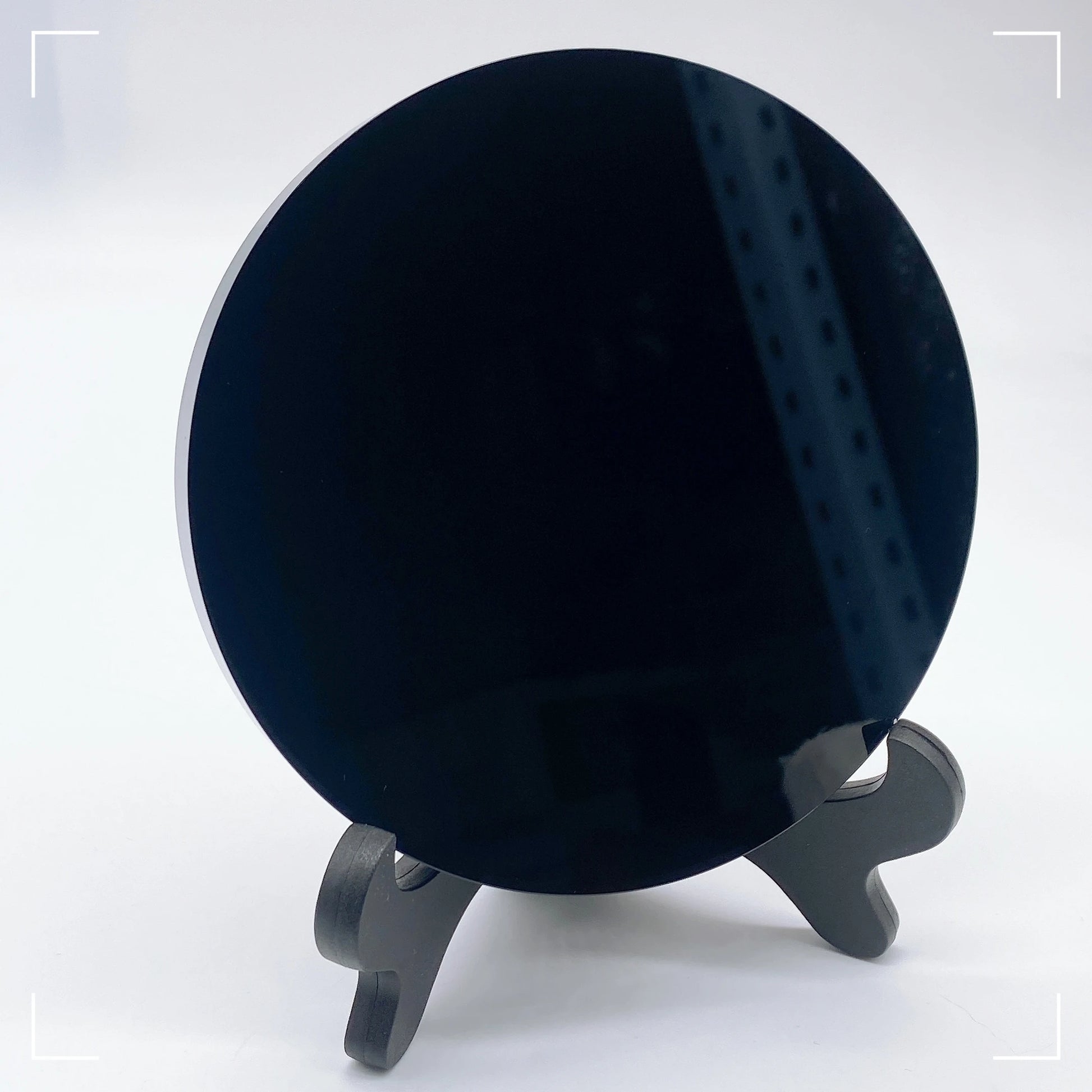 Black circular object on a stand against a white background