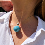 A close-up of a person wearing a silver larimar necklace