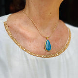 a woman wearing a super blue larimar gold necklace pendant