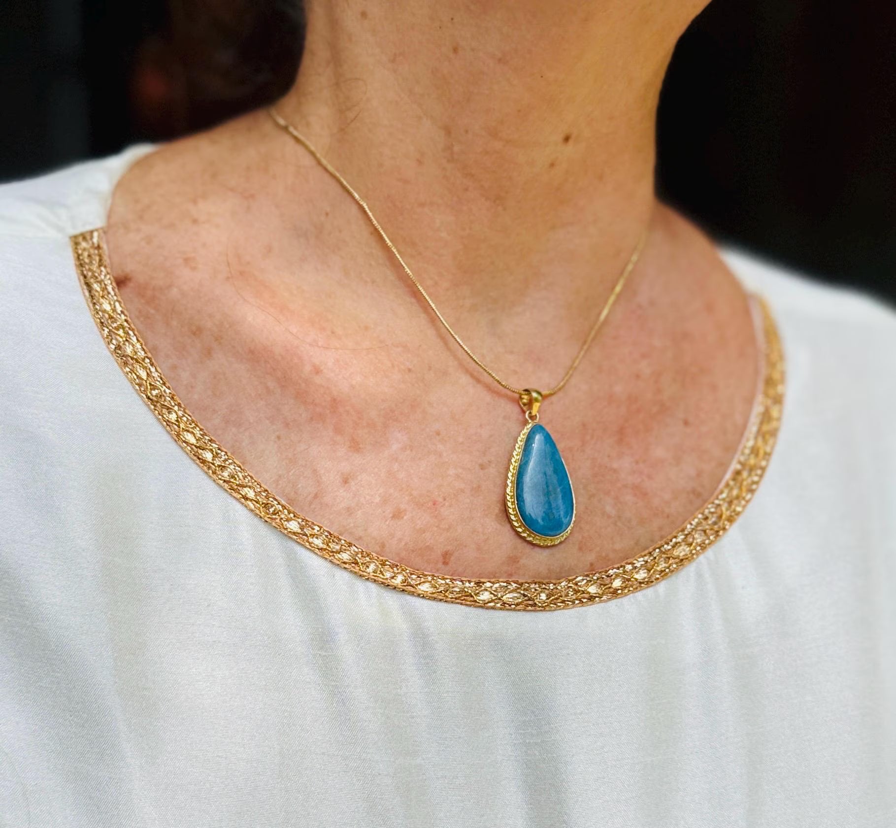 a woman wearing a super blue larimar gold necklace pendant