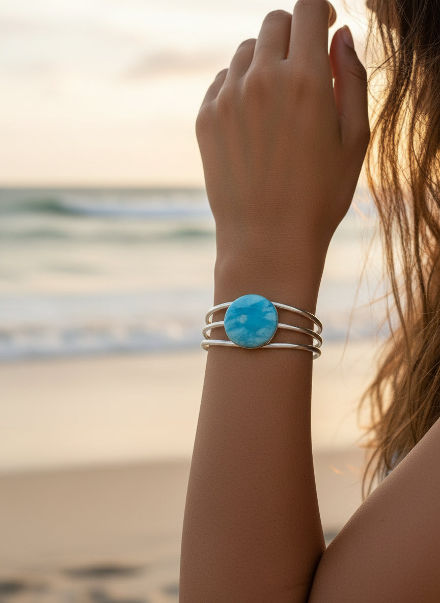 Hand holding a silver ring with a blue stone against a blurred background