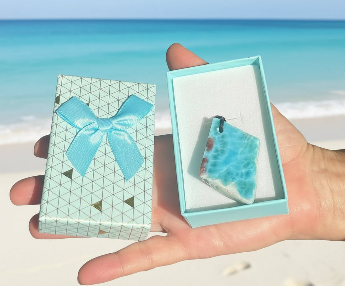 Hand holding a turquoise earring in a box with a matching bow on a patterned card.