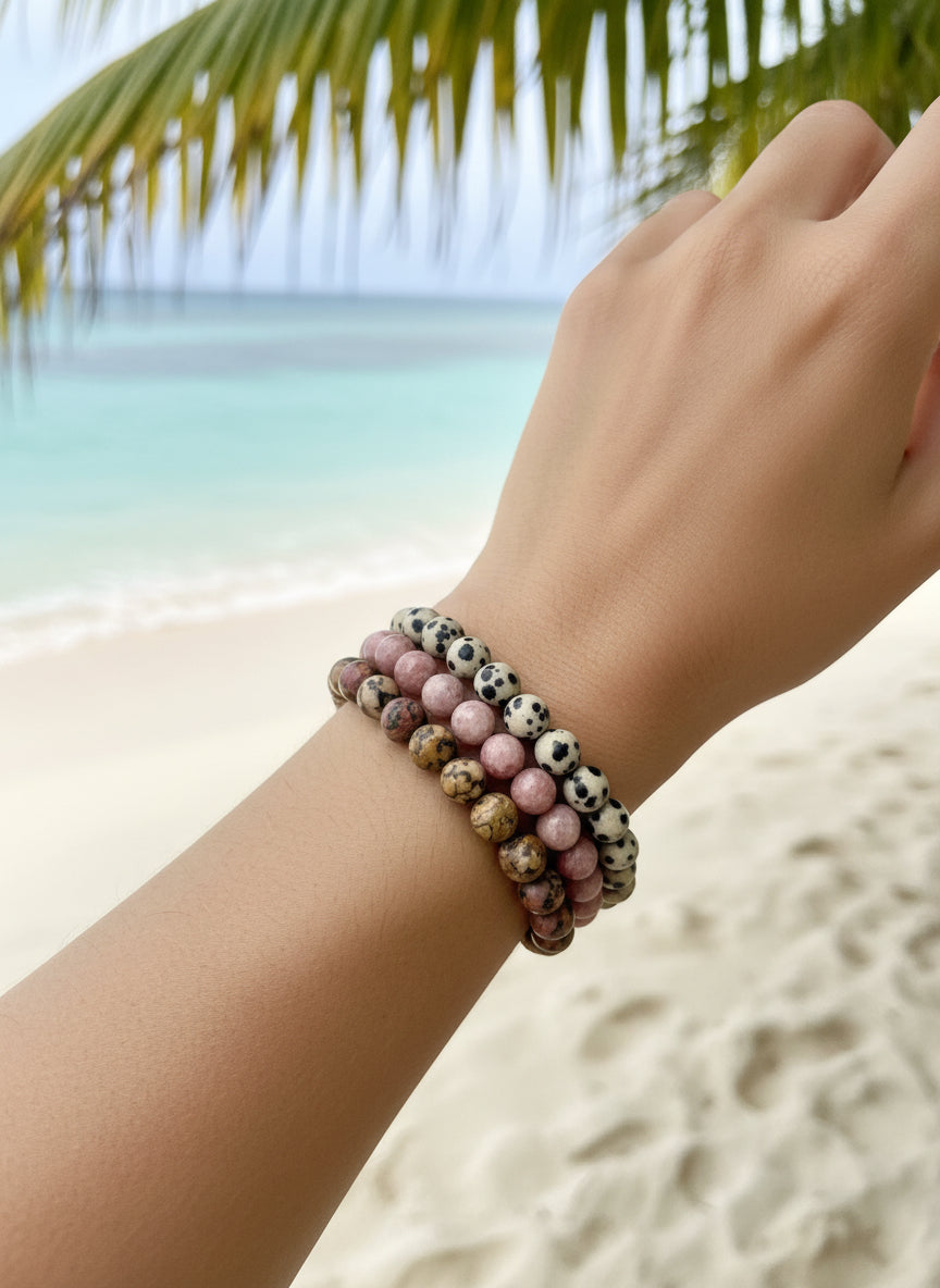 Person wearing a bracelet with pink and white beads against a green plant background