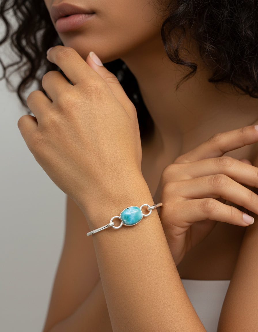 Silver bracelet with a blue gemstone held in a hand against a light background