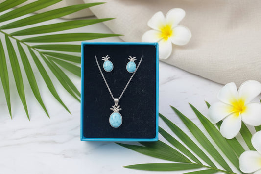 Jewelry set with pendant and earrings in a blue box held by a hand.