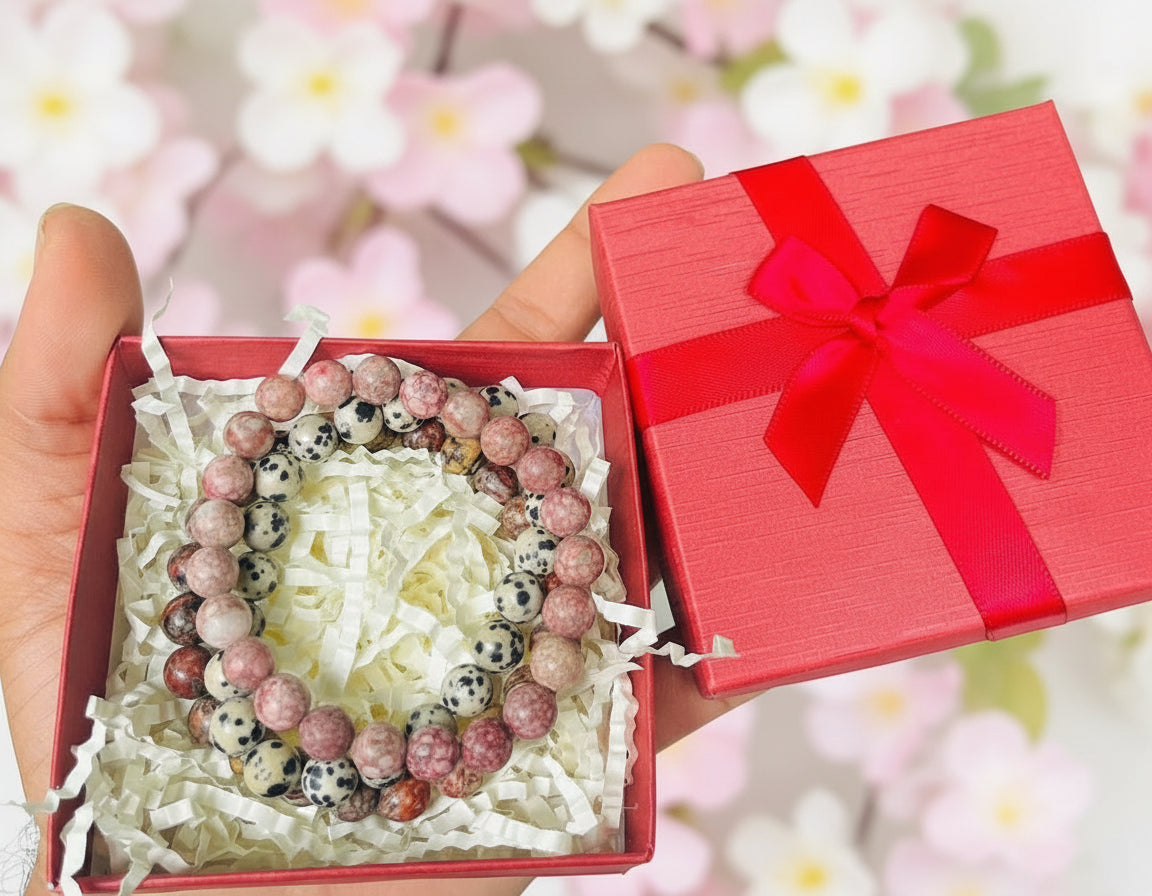 Beaded bracelet in a red gift box with a bow, held against a natural background.