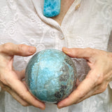 A woman holding a larimar sphere