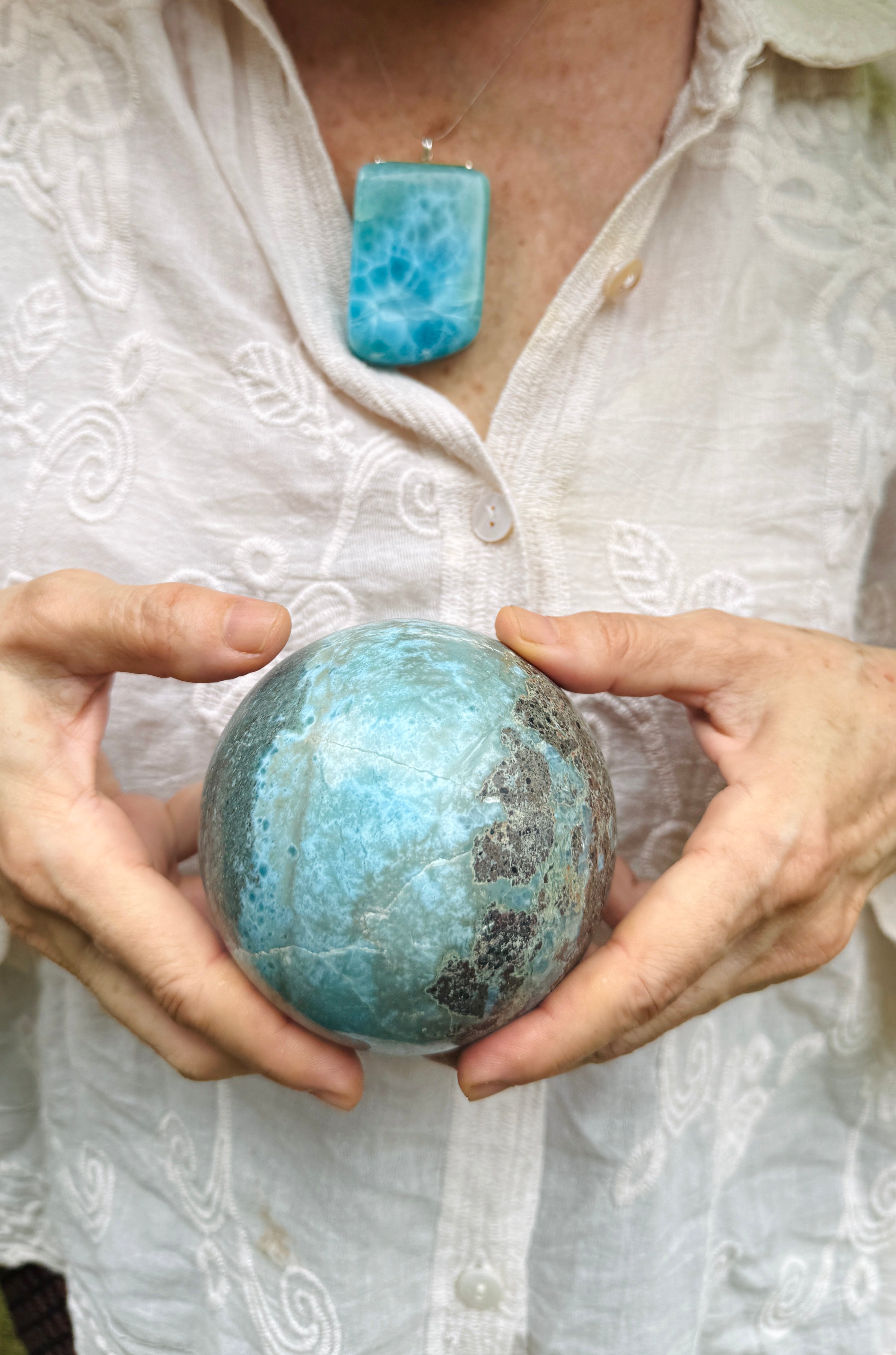 A woman holding a larimar sphere