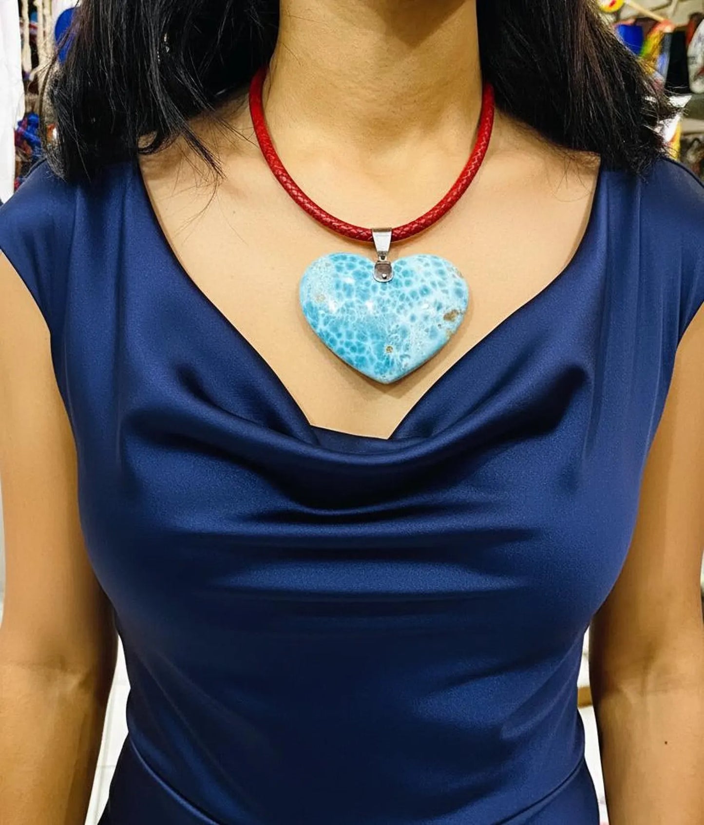 Person wearing a blue dress with a larimar necklace featuring a turquoise heart pendant.