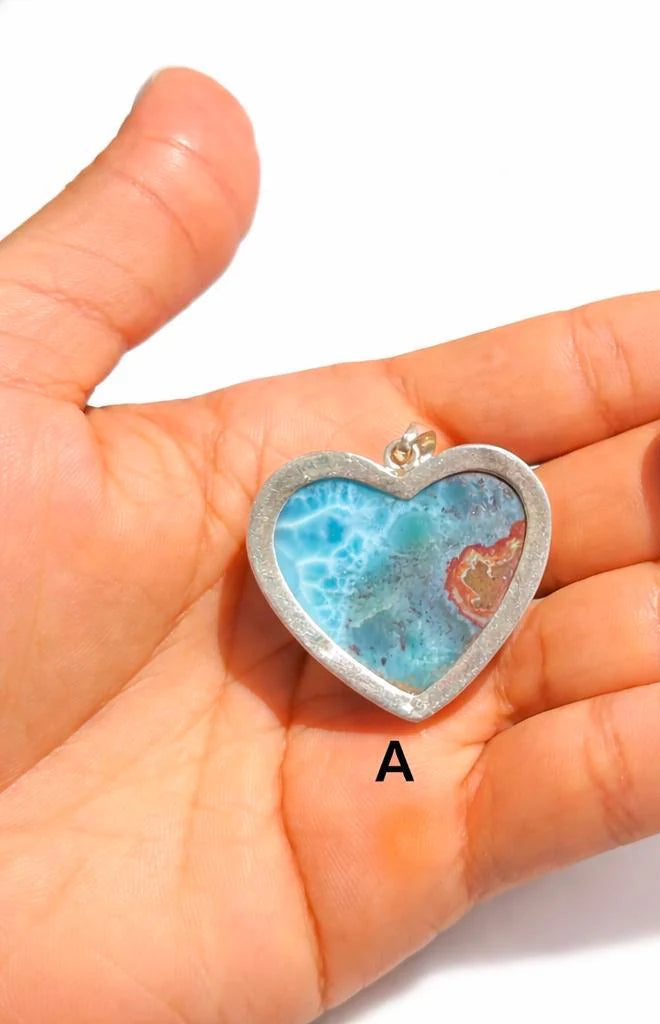 Heart-shaped blue stone pendants held in a hand with labels A and B.