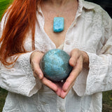 a woman holding a larimar sphere crystal ball for medition
