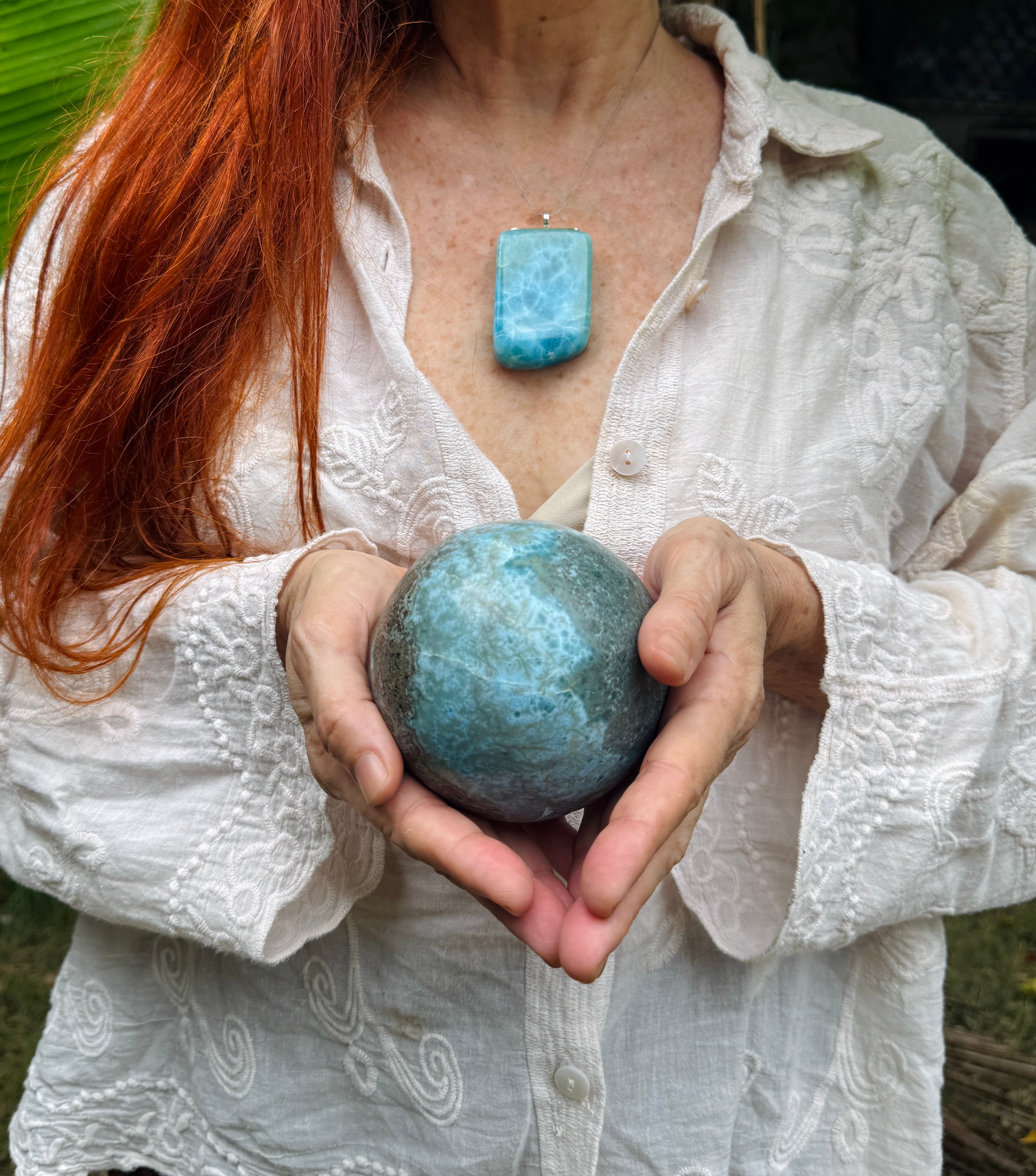 a woman holding a larimar sphere crystal ball for medition